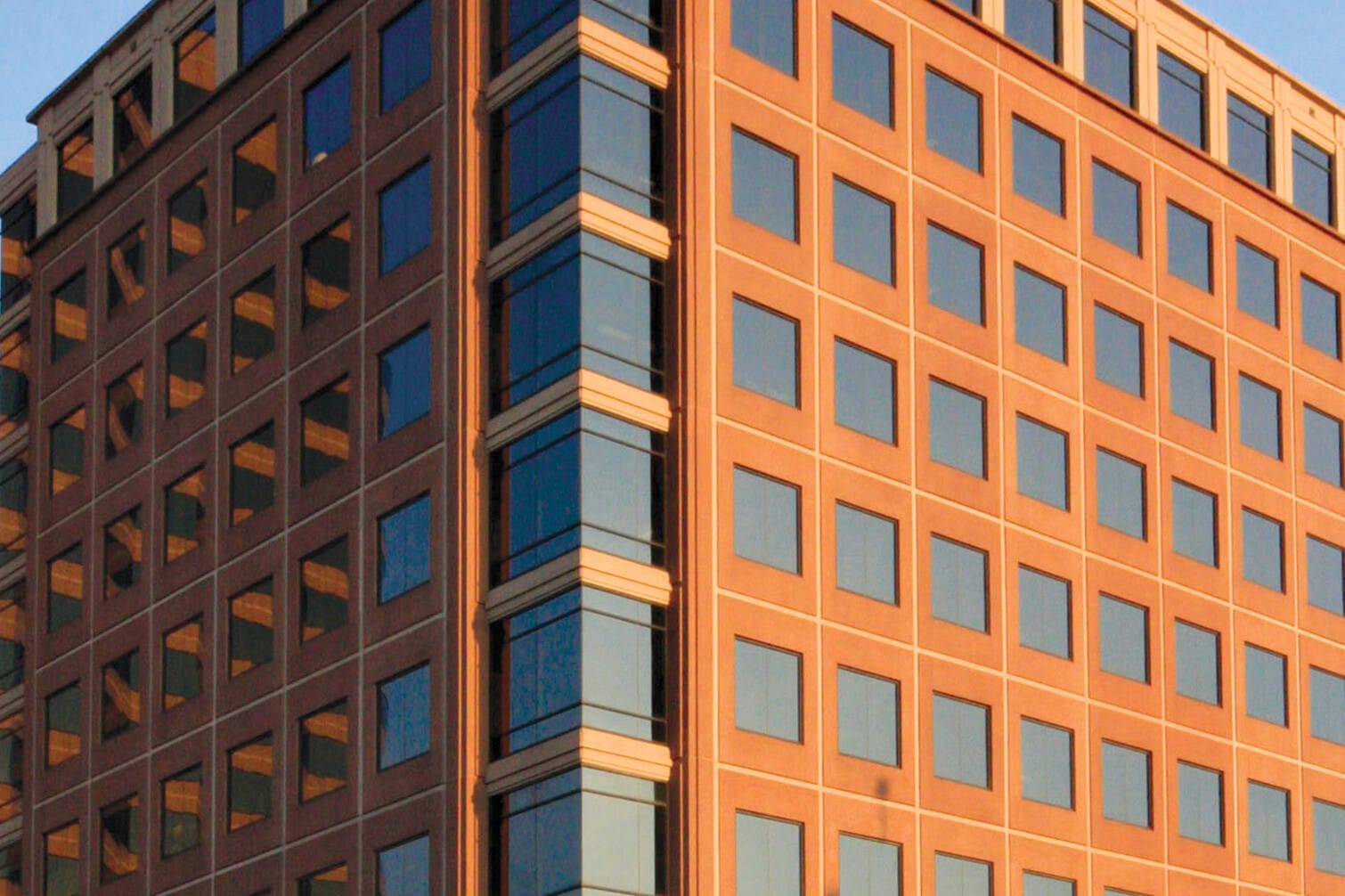 Modern orange and beige office building under clear blue sky, involved in past zero-cash-flow transactions, displaying symmetric windows and a triangular architectural feature at the top corner.