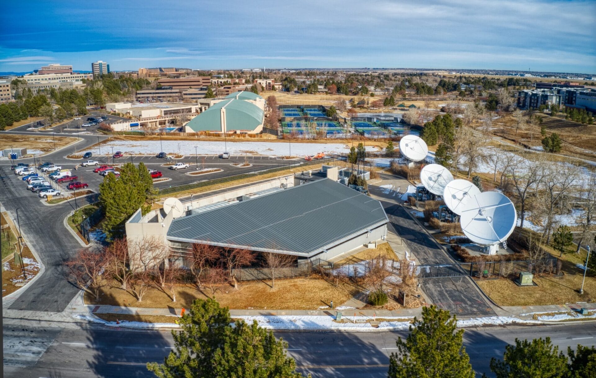 Aerial view of the DIRECTV Data Center Portfolio with buildings, satellite dishes, and a parking area, partially covered in snow.
