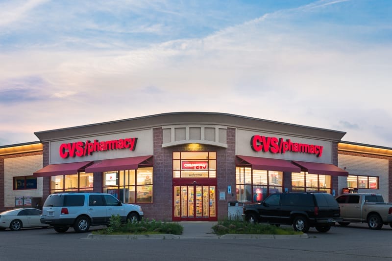 Exterior view of a CVS pharmacy store at dusk with illuminated signage and parked cars in the foreground, showcasing its presence in an unlevered portfolio.