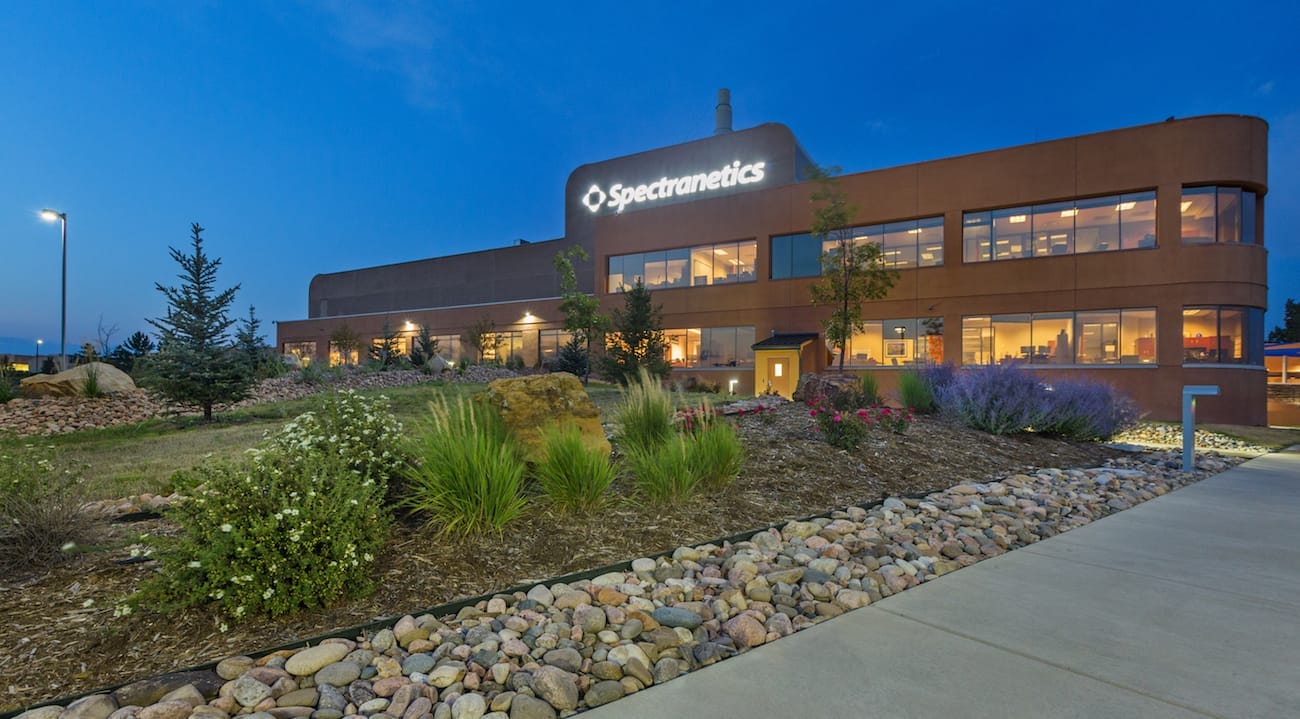 Exterior view of the Spectranetics manufacturing property at twilight, featuring illuminated signage, landscaped gardens, and a clear sky.
