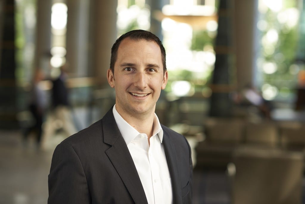 Smiling man in a suit standing in a Yahoo Finance lobby with blurred background.