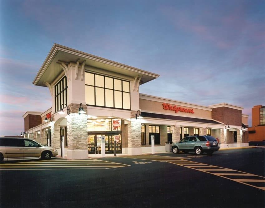 Evening view of a Walgreens store, a prime example of commercial real estate with illuminated signage, a parked car, and clear skies, showcasing the building's modern architecture.