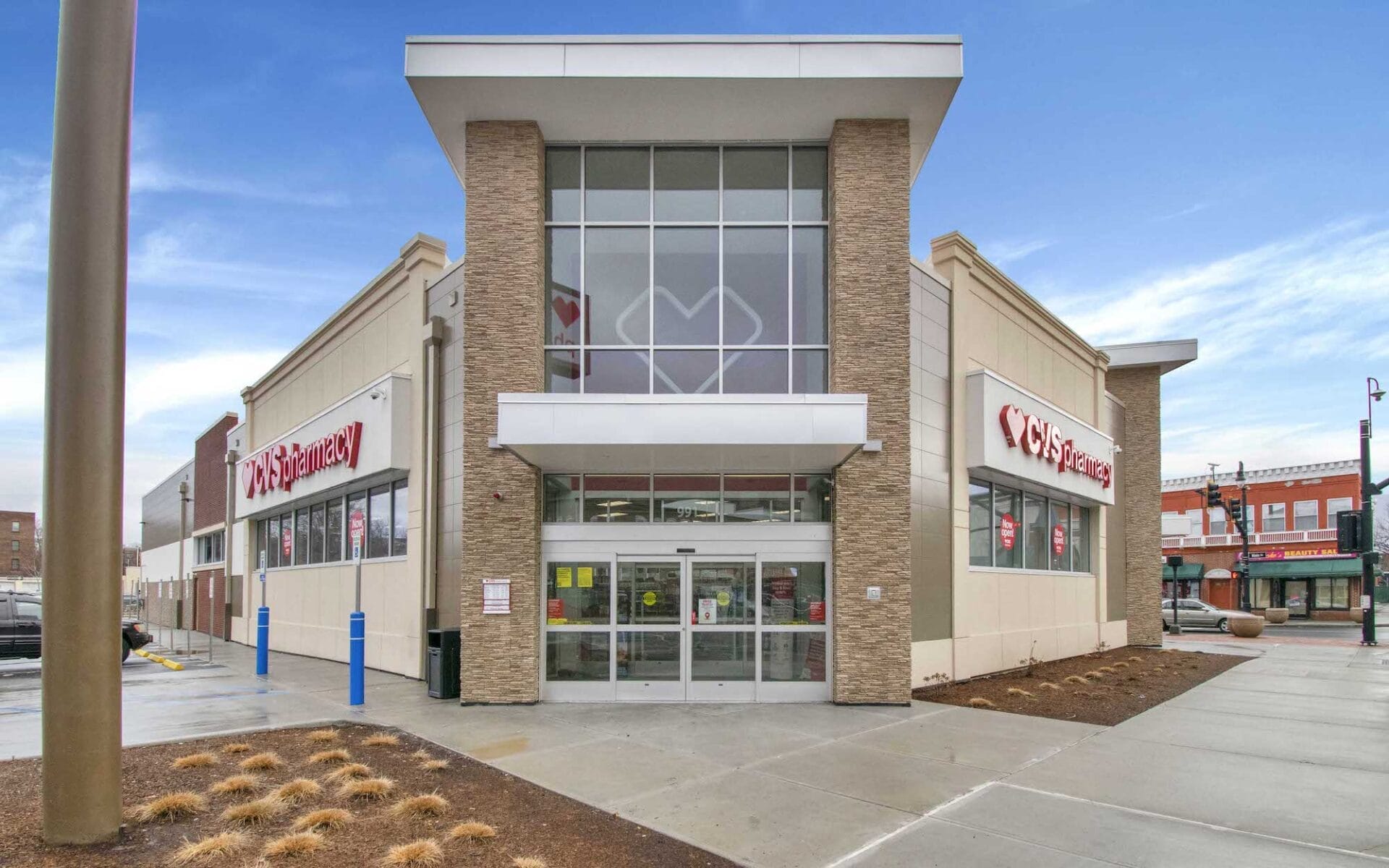 Exterior view of a CVS Pharmacy leasehold closing in Belle Mead, New Jersey, featuring a large entrance with glass doors and two smaller storefronts under a cloudy sky.