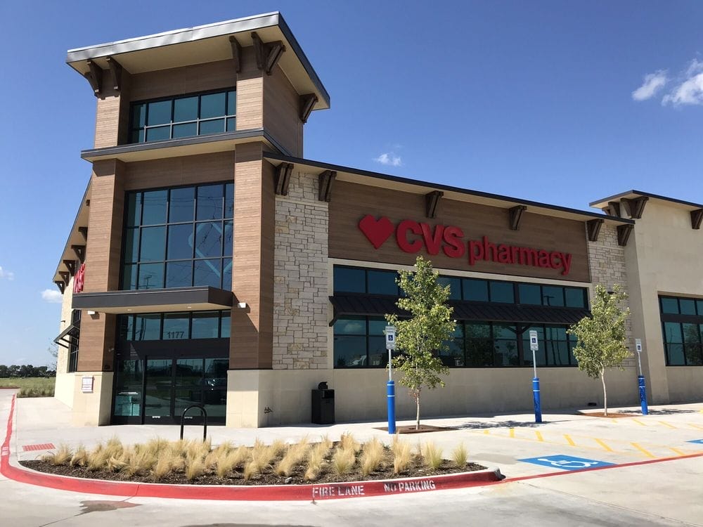 Exterior of a CVS Pharmacy store in Frisco with modern design, featuring large windows and a prominent red logo, located in a sunny parking lot.