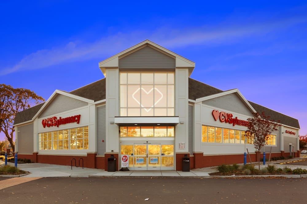 Exterior of a CVS pharmacy store at twilight, featuring a well-lit facade with large windows and signage, part of the 47-property CVS portfolio sale.