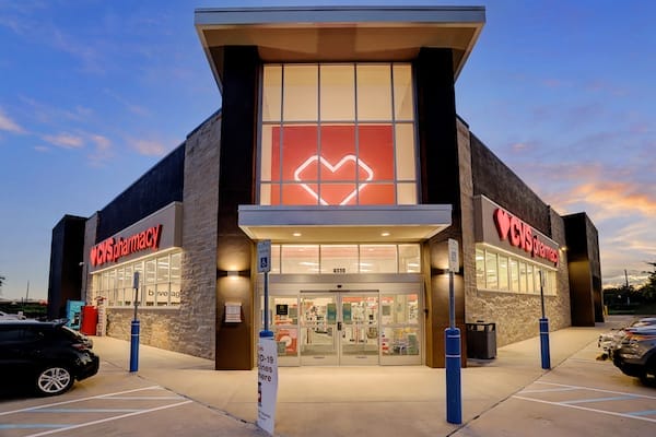 Exterior view of a recently sold CVS pharmacy store in Richmond TX at dusk with illuminated signage and a parking lot in front.