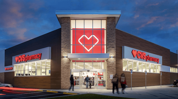 Exterior view of a CVS Pharmacy store in Zapata, TX at dusk, featuring a brightly lit entrance and prominent red CVS logos on the building.