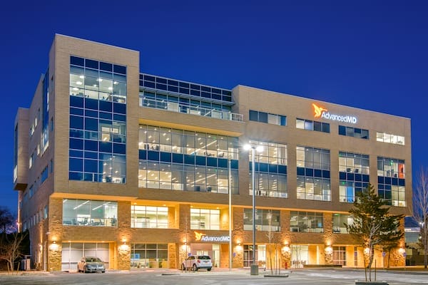 Exterior view of the advancedmd office building in the Salt Lake City MSA, illuminated at dusk, featuring prominent signage and a modern design with multiple windows.