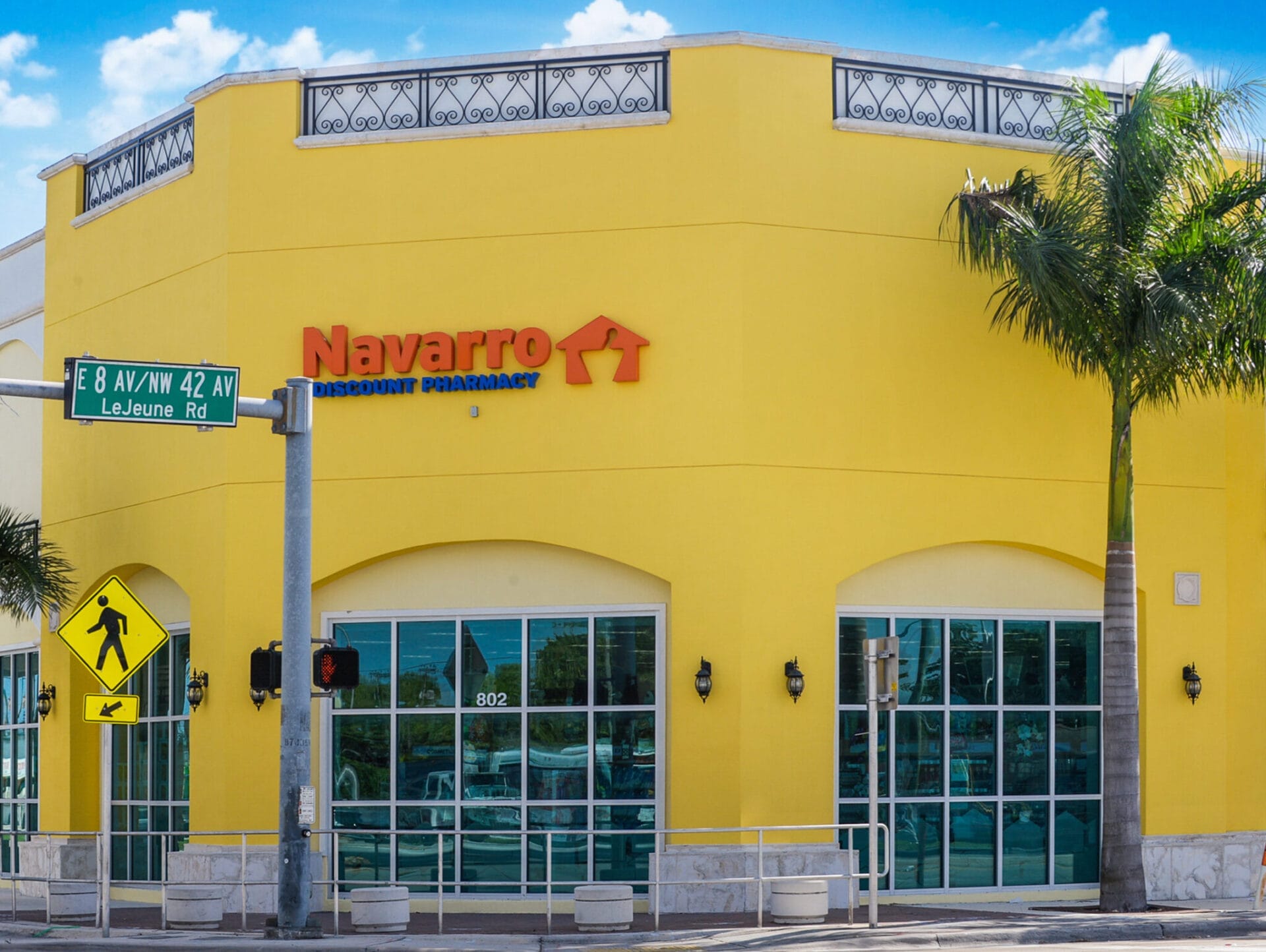Exterior of a recently sold Navarro Discount Pharmacy (CVS) store with a bright yellow facade, located at the corner of a street in Hialeah, FL, under a clear blue sky