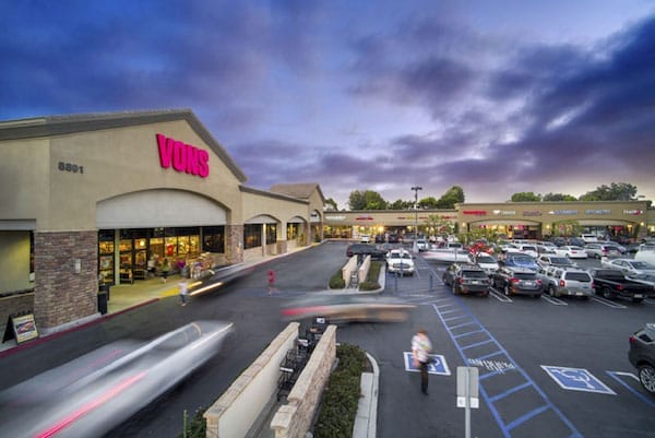 Twilight view of a busy Vons Grocery Store parking lot in Huntington Beach with cars in motion and dramatic clouds above.